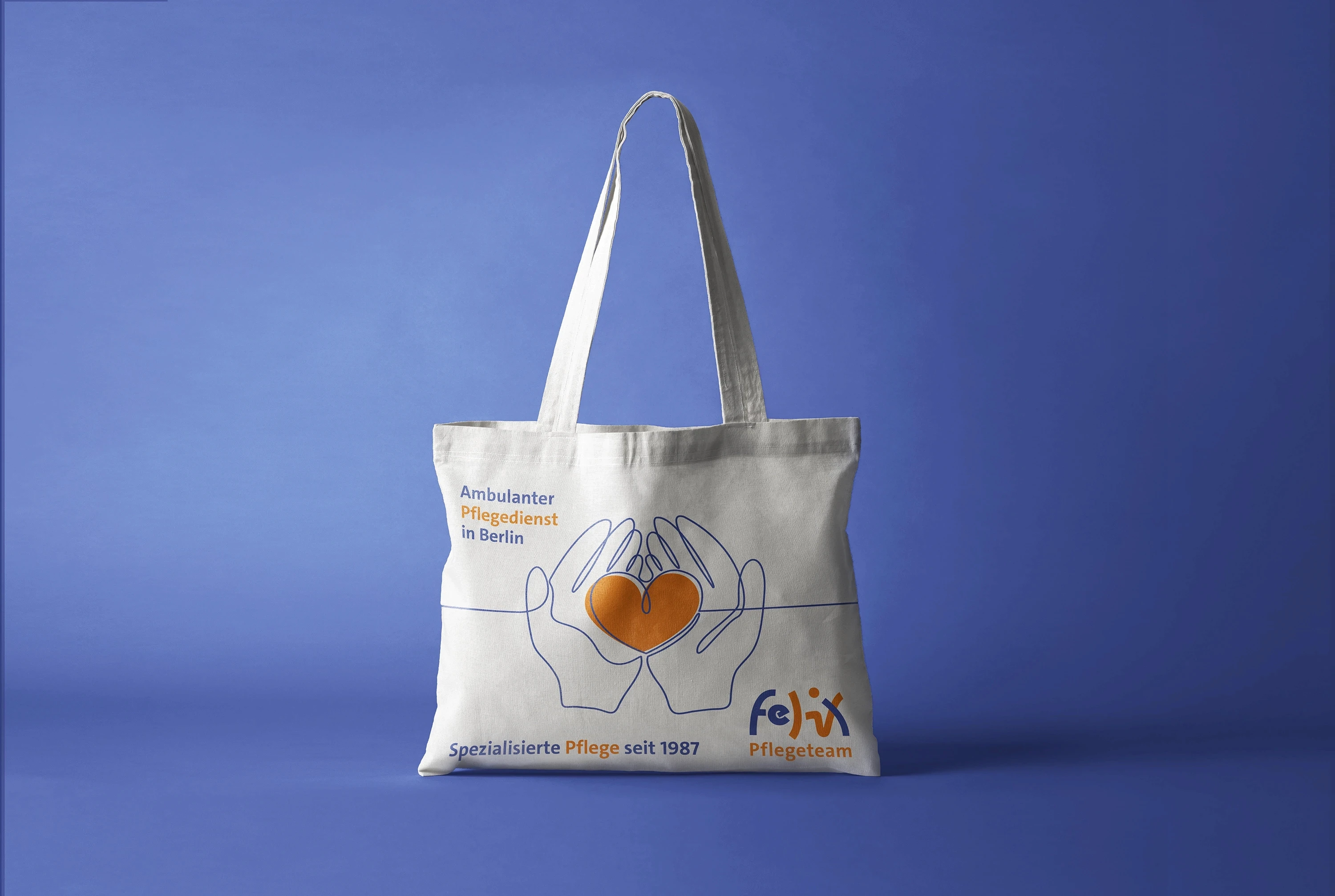 Felix Pflegeteam Jutebeutel Mockup: Stoffbeutel mit Herz-in-Händen-Logo für ambulanten Pflegedienst Berlin, freigestellt auf blauem Hintergrund