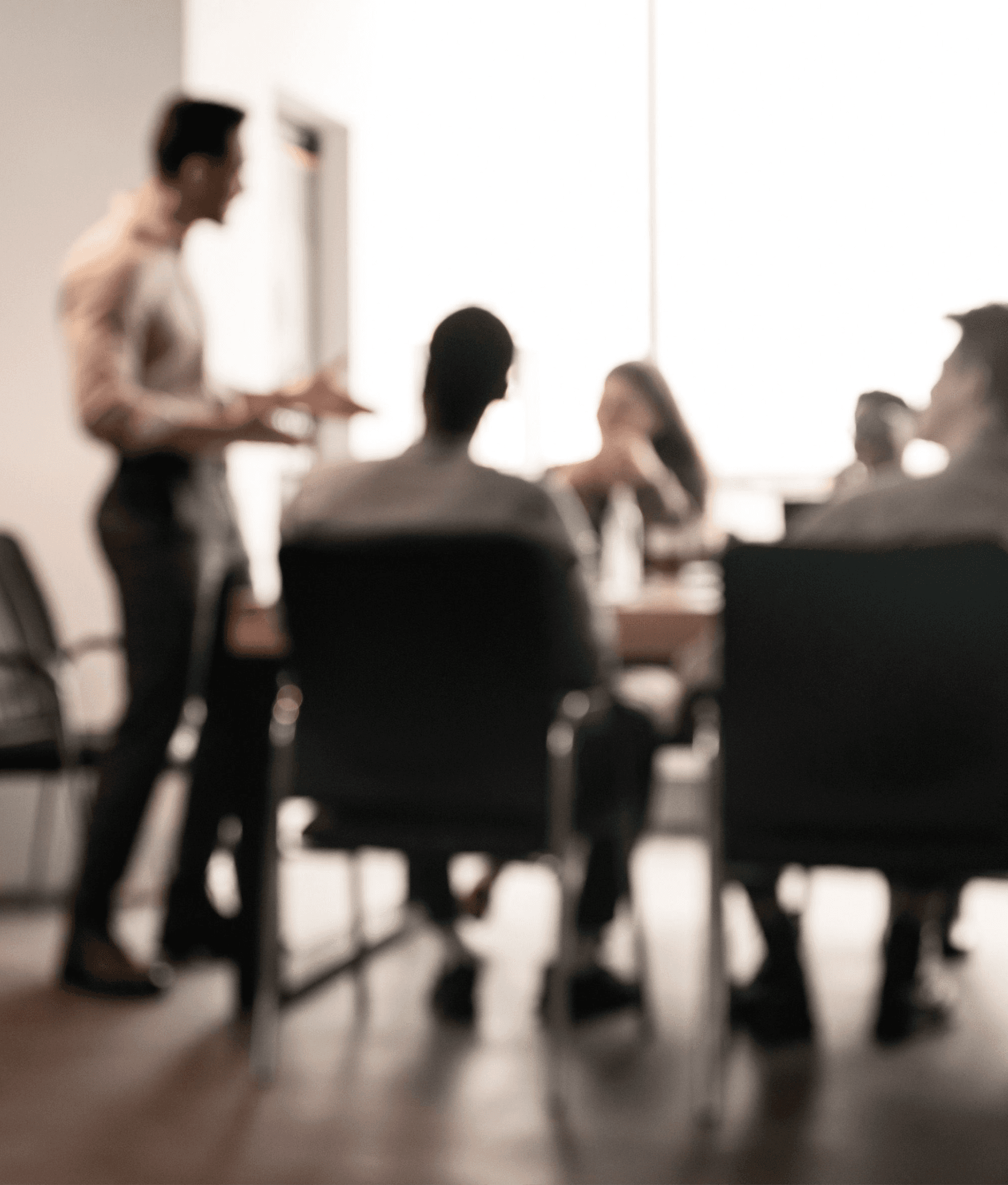 Imagem borrada, com algumas pessoas conversando em uma mesa em um ambiente empresarial