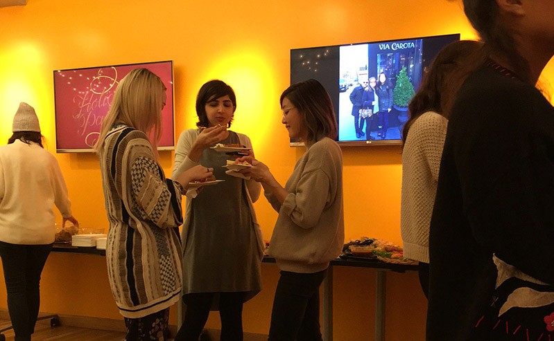 a group of people is having a snack in an exhibition room with flat-screen tv behind them