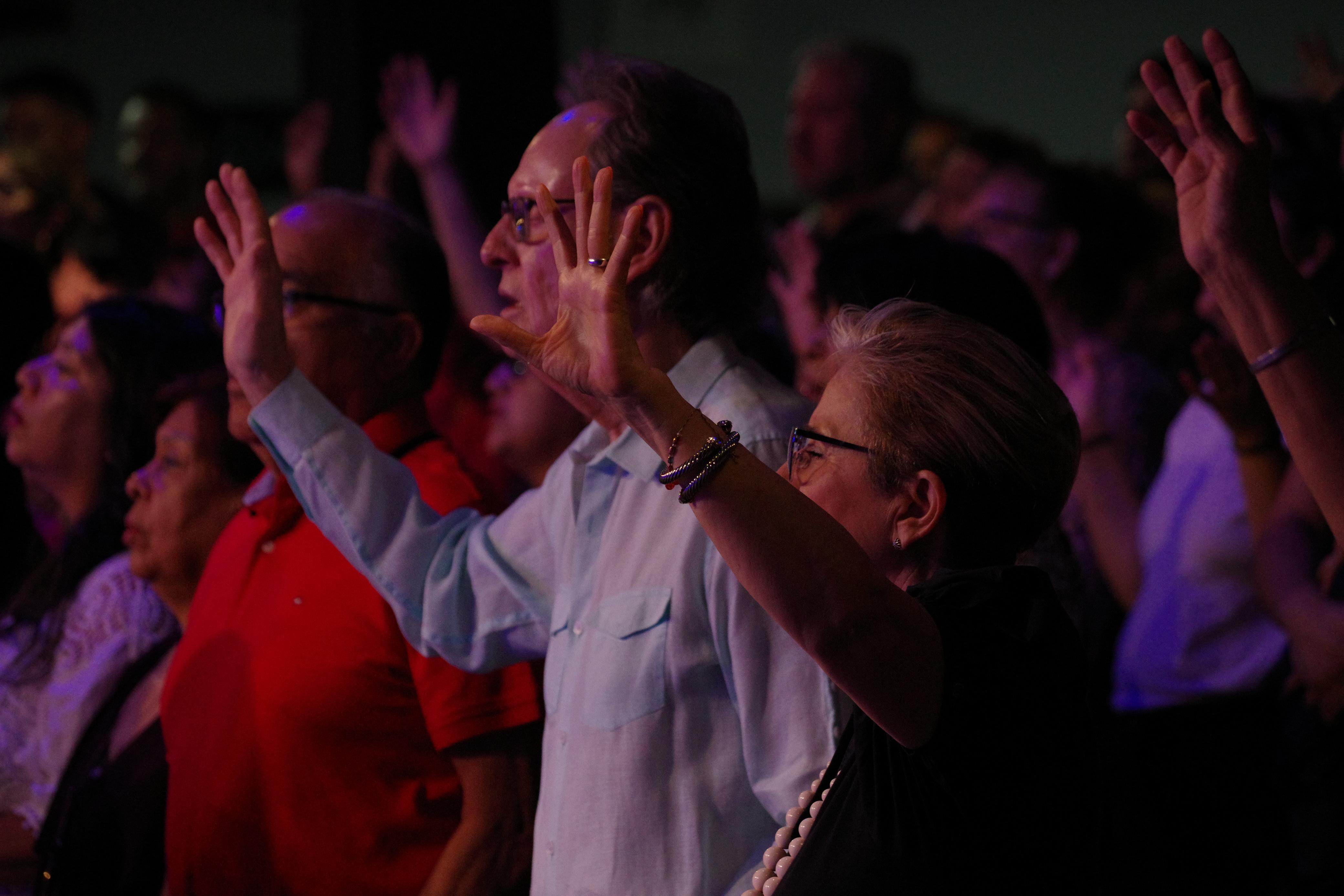 A group of four people standing outside a building, engaging in conversation, with cars parked nearby.