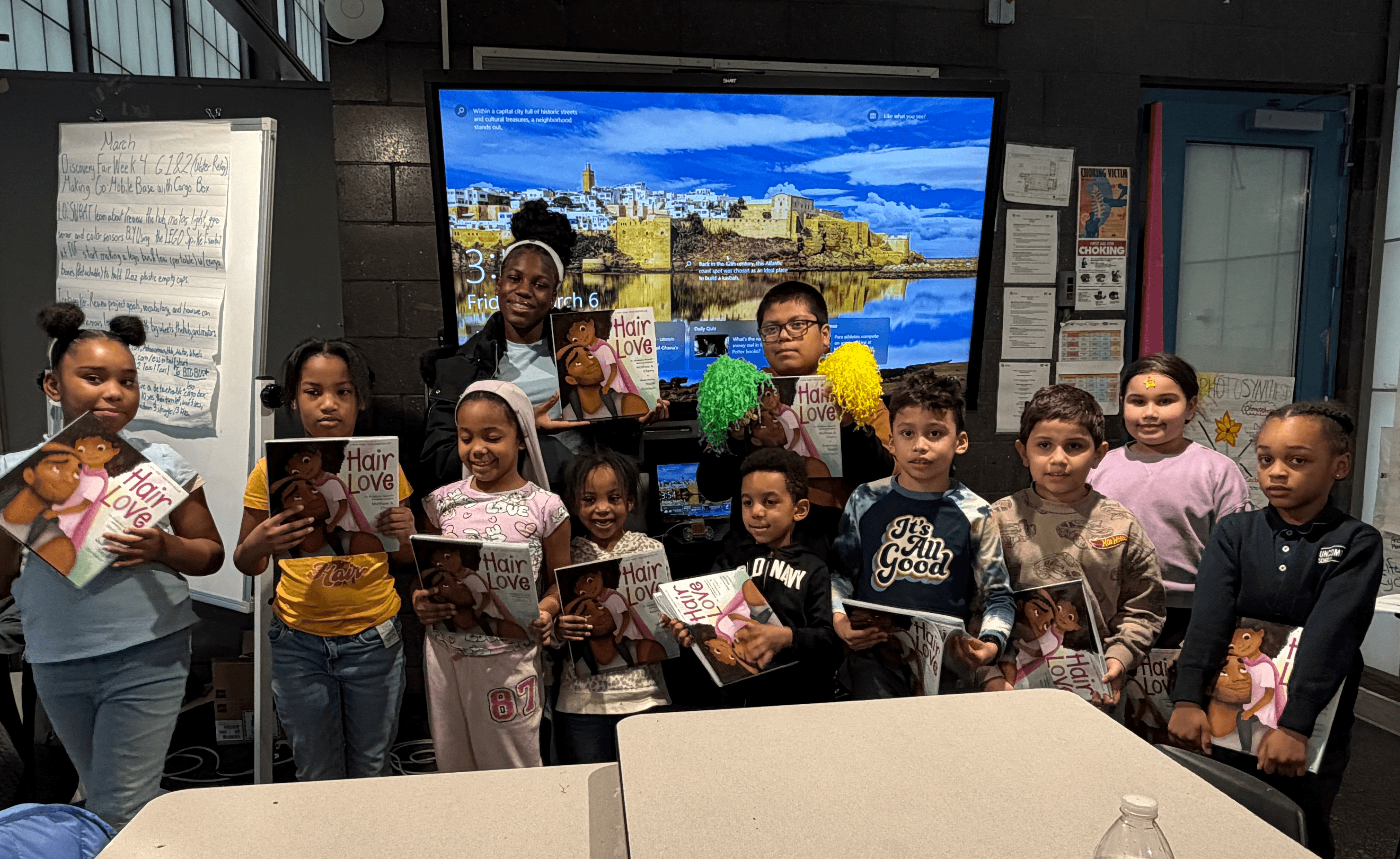 A group of teens and elementary school kids all holding the book Hair Love.