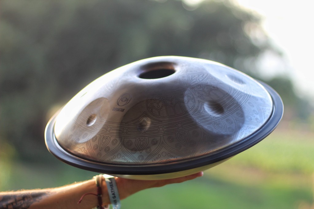 A person holding a premium travel handpan in the air.