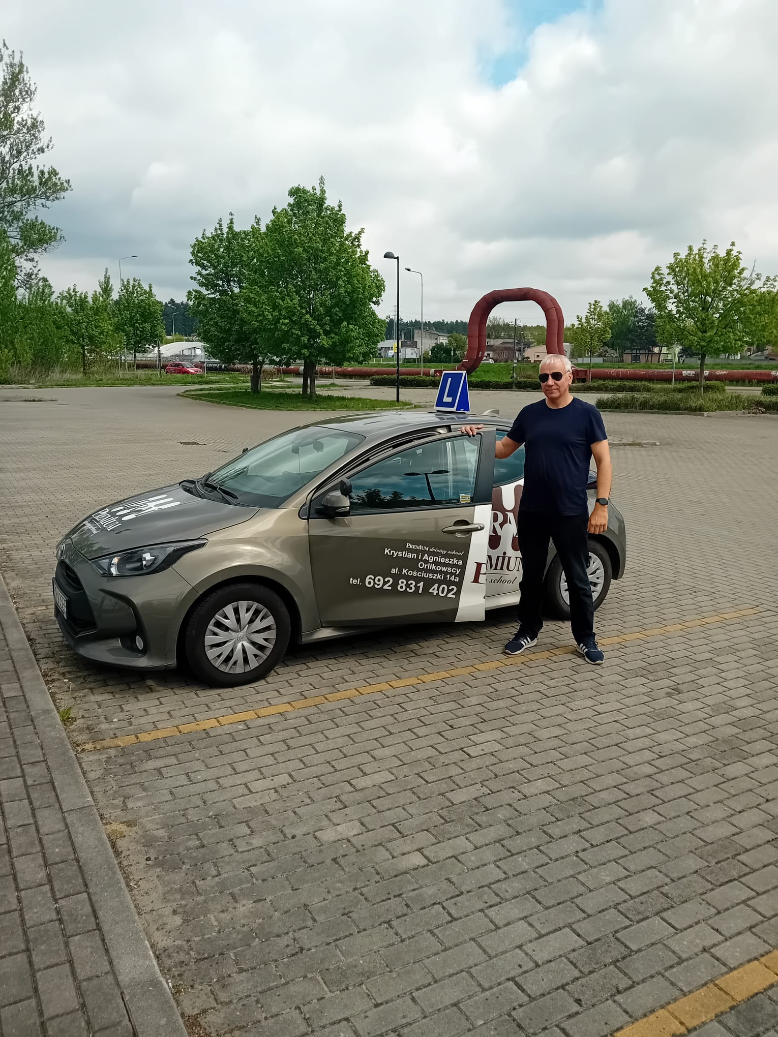 Darek Wilk – Instruktor stojący obok Toyoty Yaris z logo szkoły Premium.