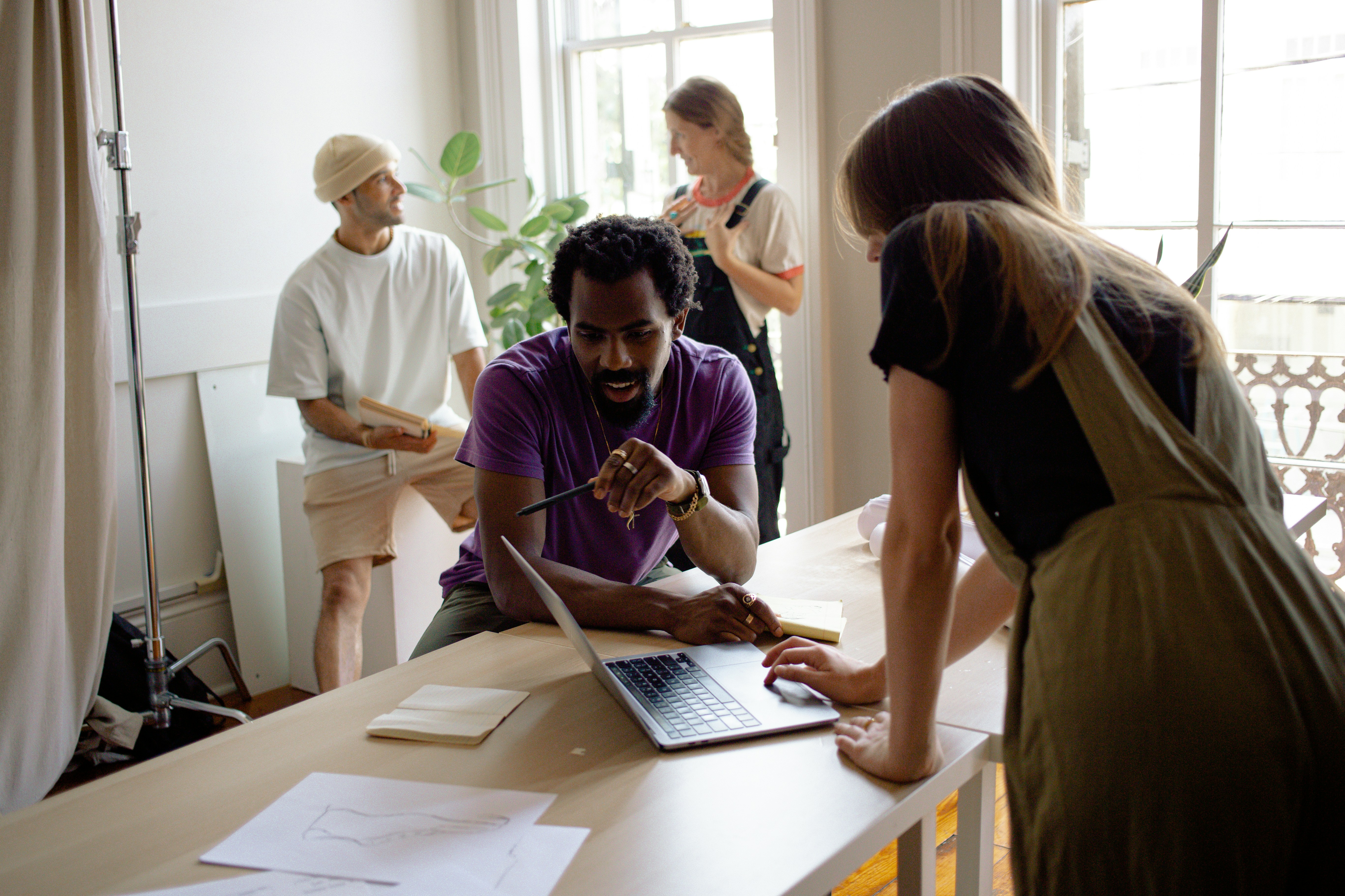 A group of people collaborating around a table with papers in a bright, airy room.