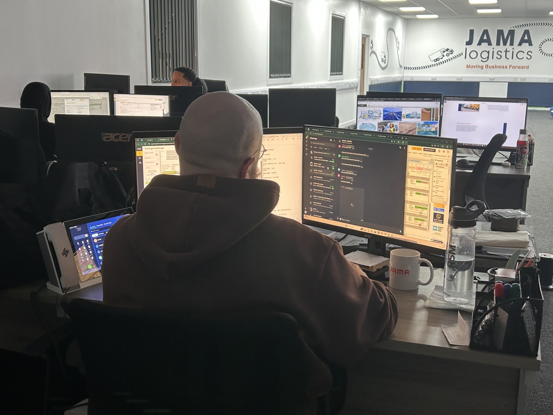 image of a person working in an offcie looking at a monitor with the jama logistics logo on the wall