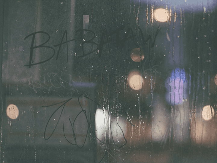 A rainy window at night with blurred city lights, illustrating an article about writing sharp dialogue.