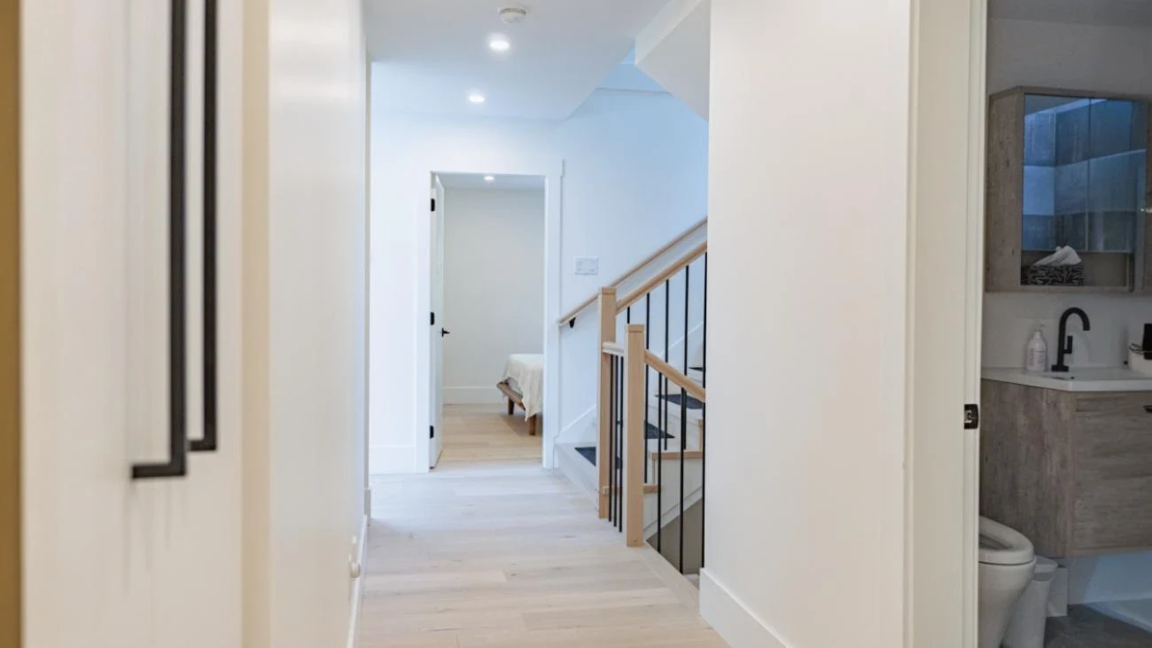 Bright upper level hallway with hardwood floors, modern staircase railing, and natural light in Vancouver custom built home