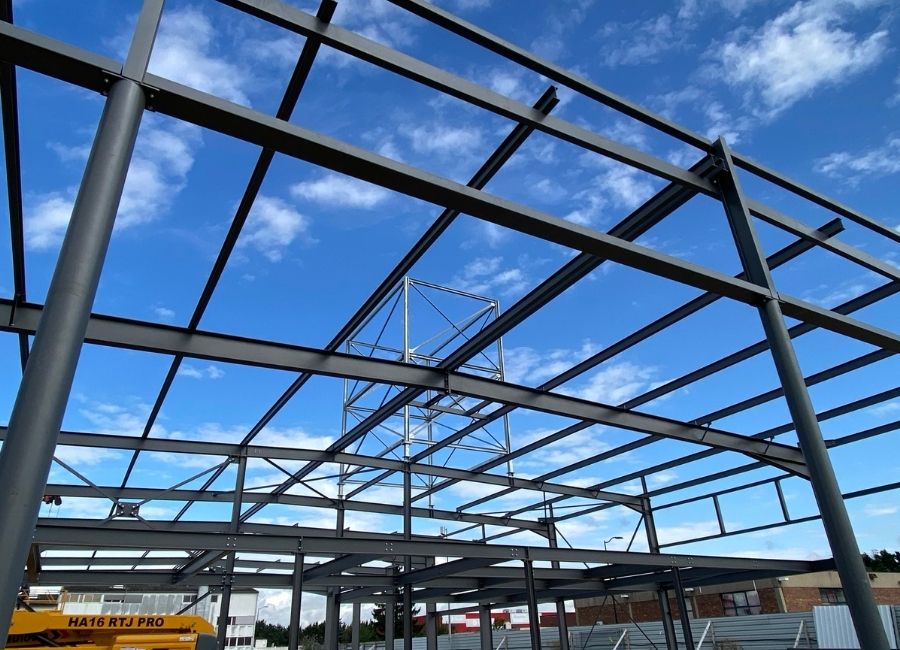 Charpente métallique en cours d’assemblage avec ciel dégagé en arrière-plan.