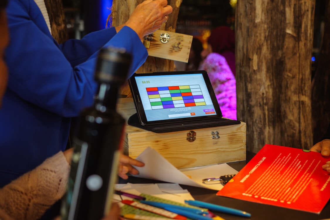 Teambuildingactiviteit op locatie van The Box Company waarbij een team een puzzel oplost met een tablet en een houten kist.
