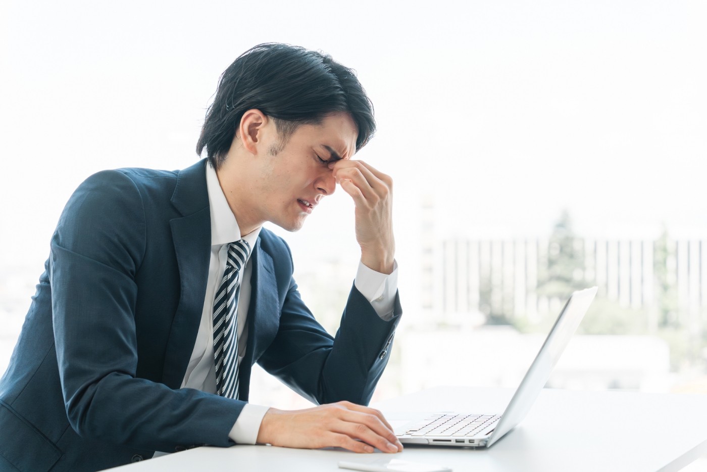 目頭を押さえて苦しそうにする男性