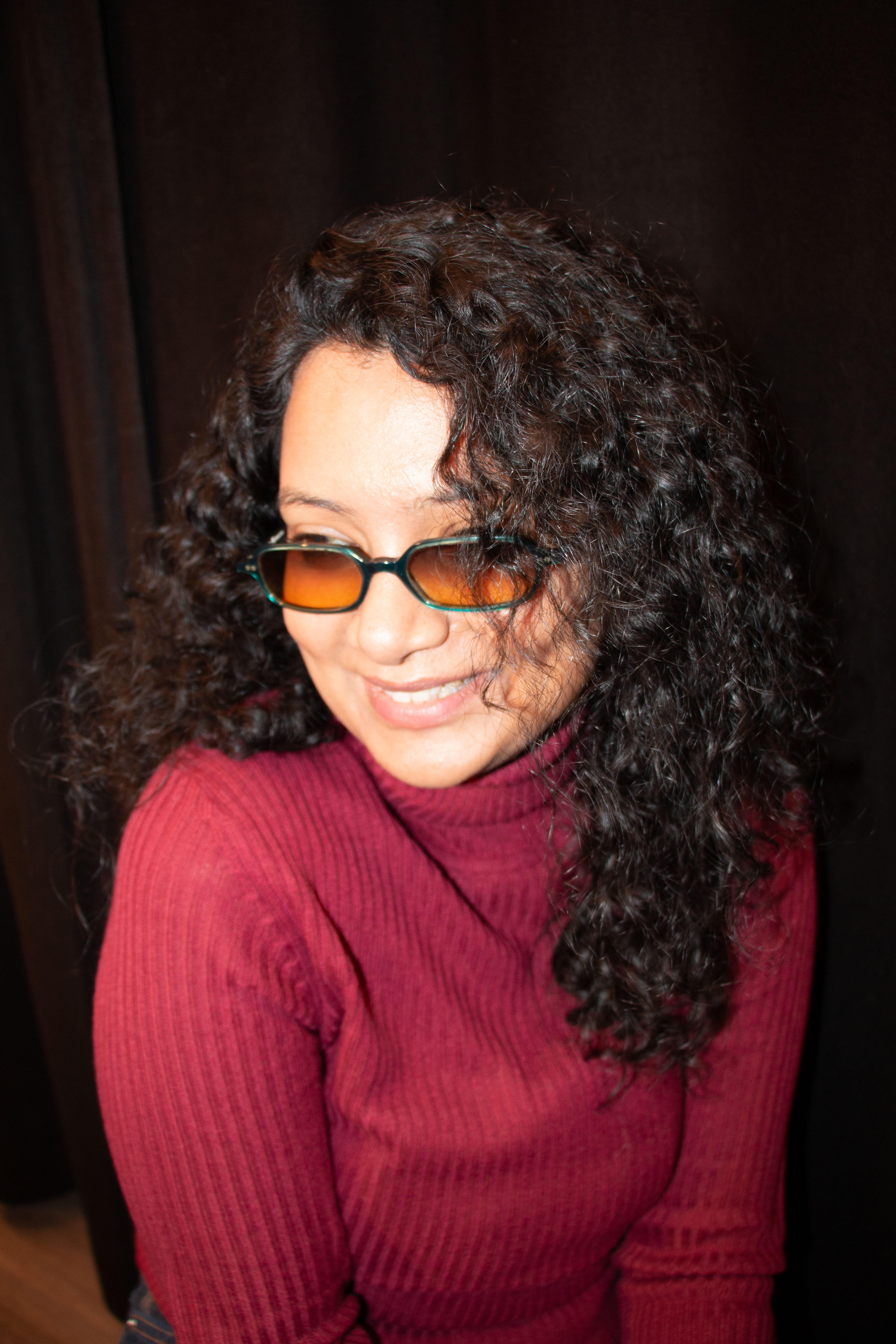 A thoughtful young person with dark hair gazes to the side, captured in soft black and white lighting.