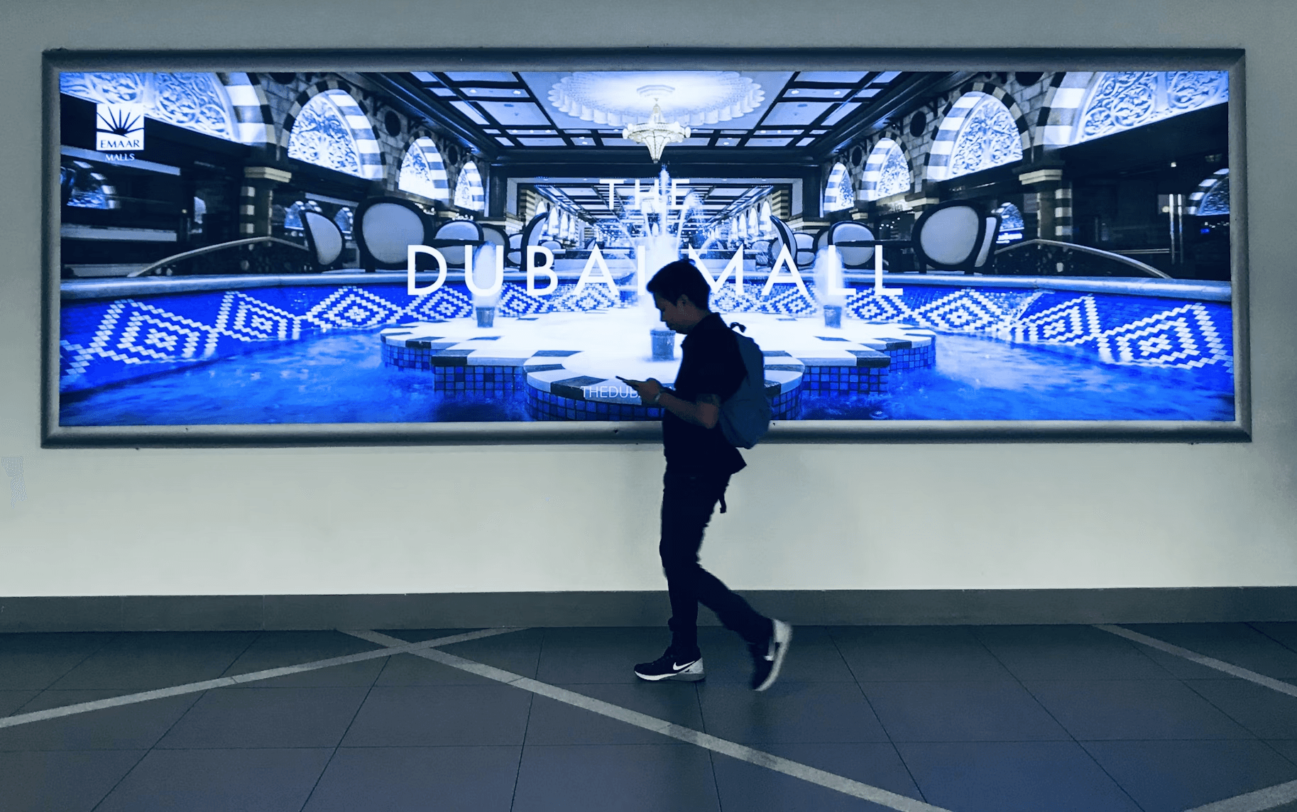 Man walks past The Dubai Mall advertisement