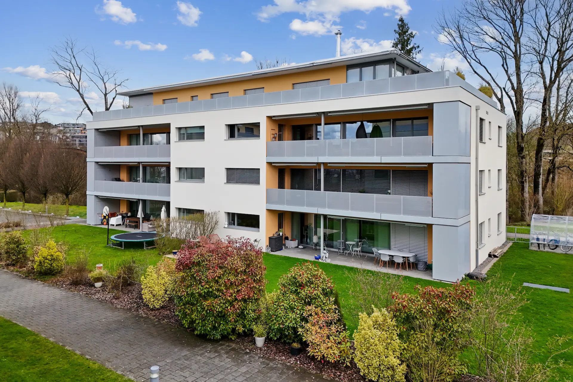 Symmetrisches Mehrfamilienhaus mit gedeckten Balkon und Terrassenbereichen