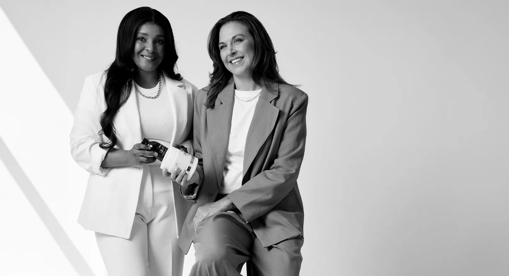 Sēkret founders Roz and Zola with a tub of Pure and a bottle of Queen, in black and white