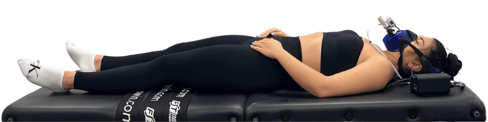 A female client laying down on a bed taking the resting metabolic test