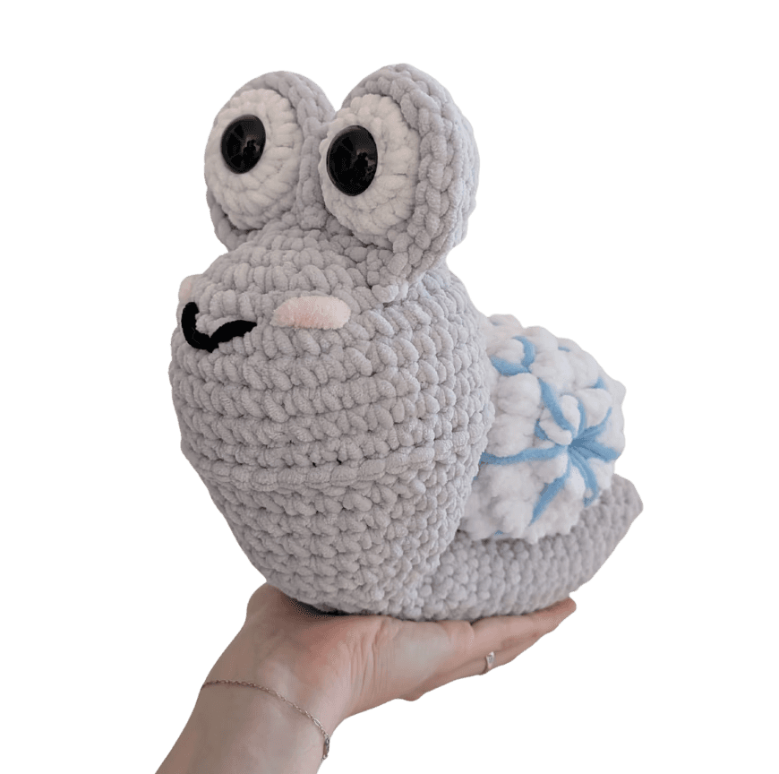 A cute, handcrafted plush hedgehog toy with brown yarn spikes and large, friendly eyes sits facing forward on a white background.