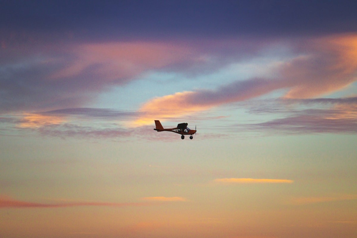 Small aircraft flying through sunset clouds