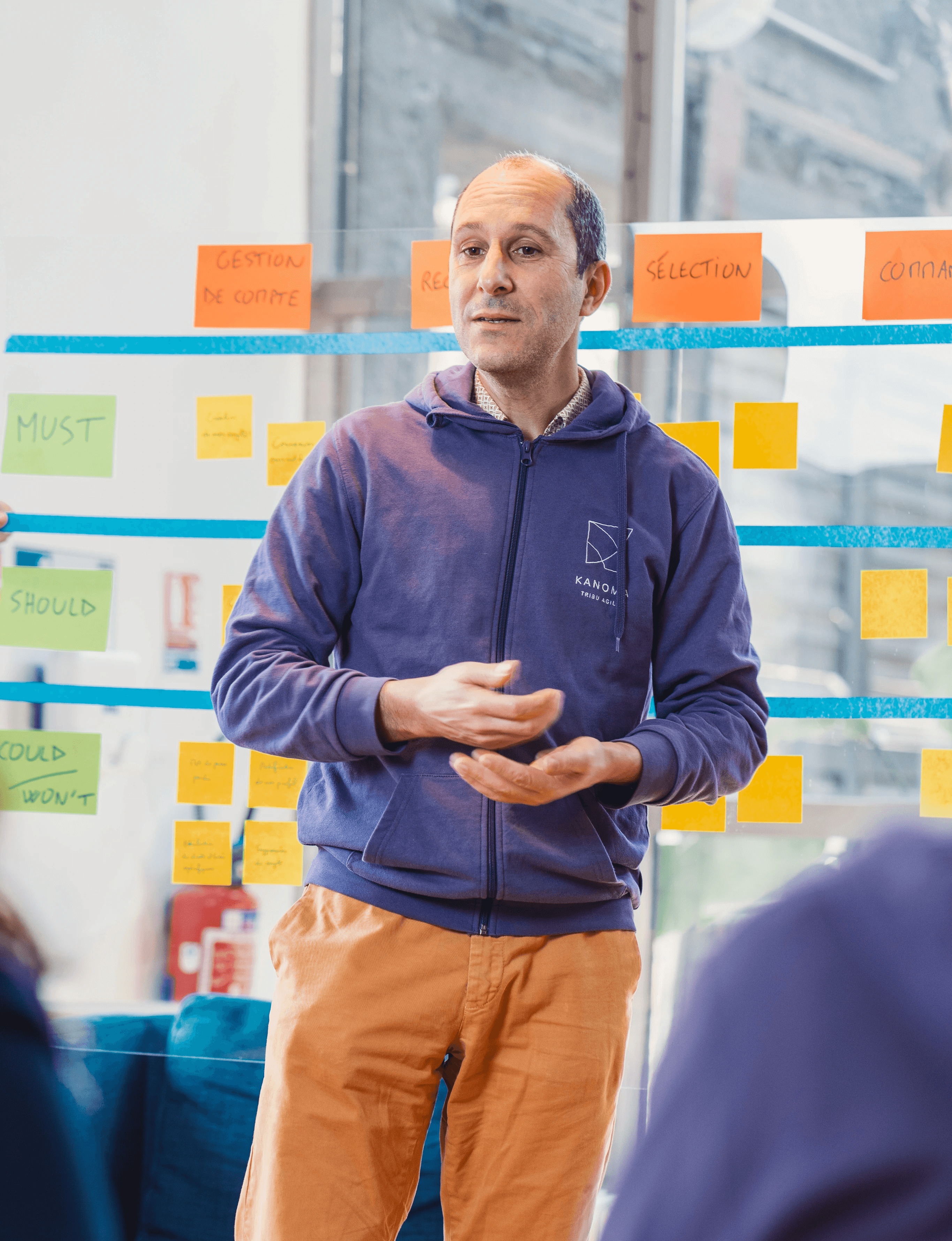 homme en sweat violet qui présente un atelier de travail