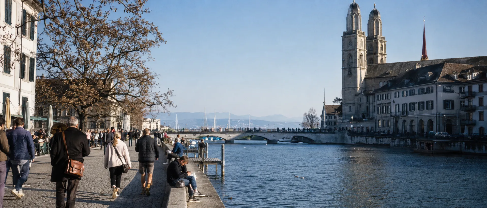 Zürcher Limmatquai mit Grossmünster, Flussufer und Spaziergängern im Morgenlicht