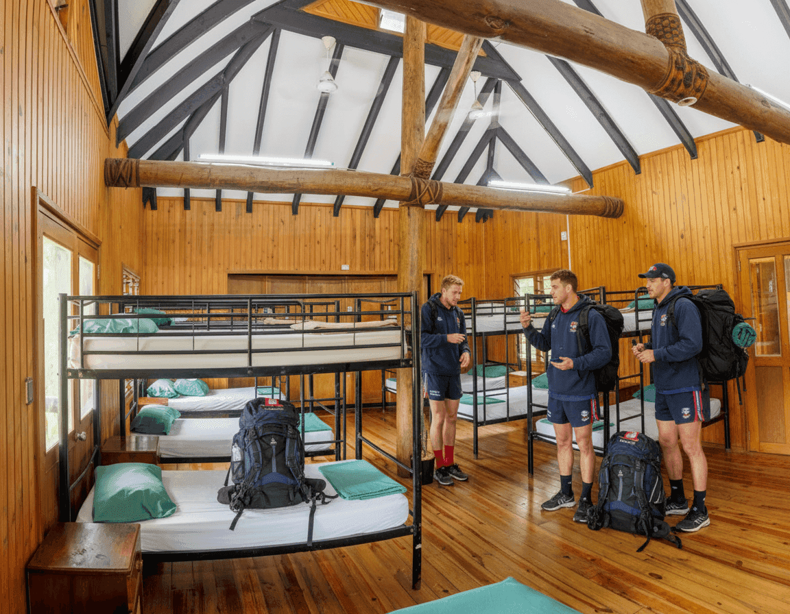 Sports buddies talk inside their bunk bed dorm after putting their bags down