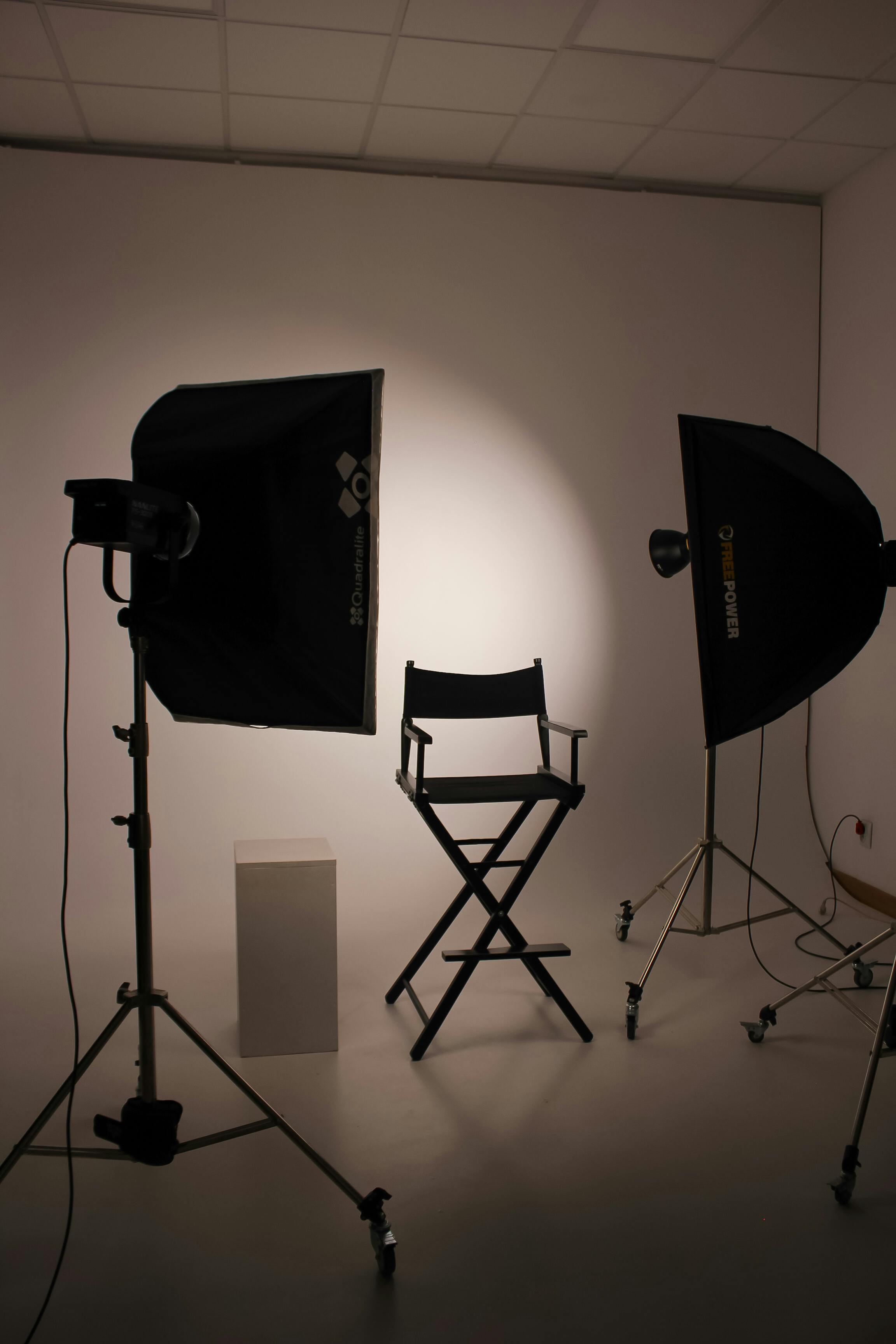 Photography studio with two black softboxes and a director’s chair