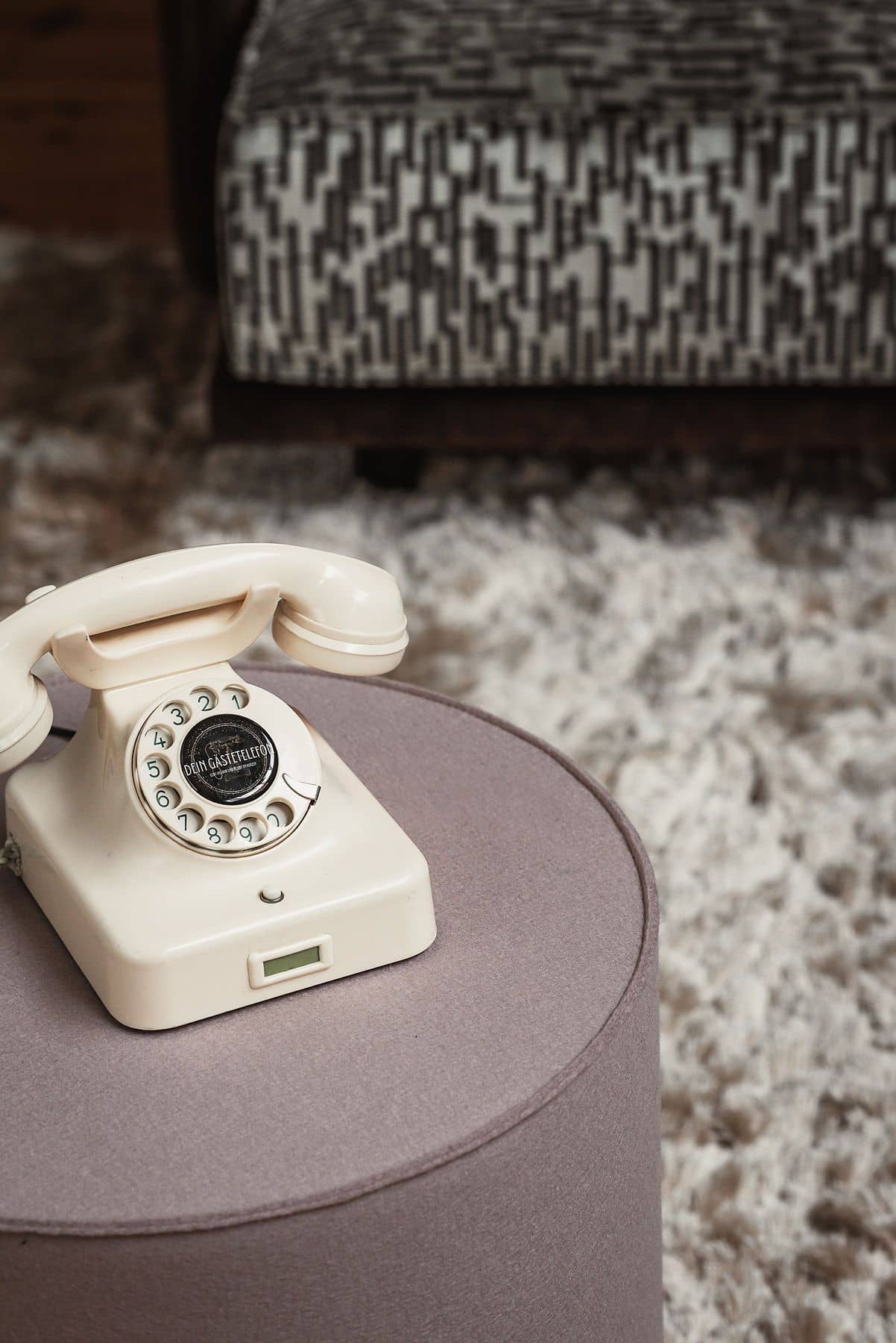 Gästetelefon Ivory auf einem Hocker vor einem Sessel