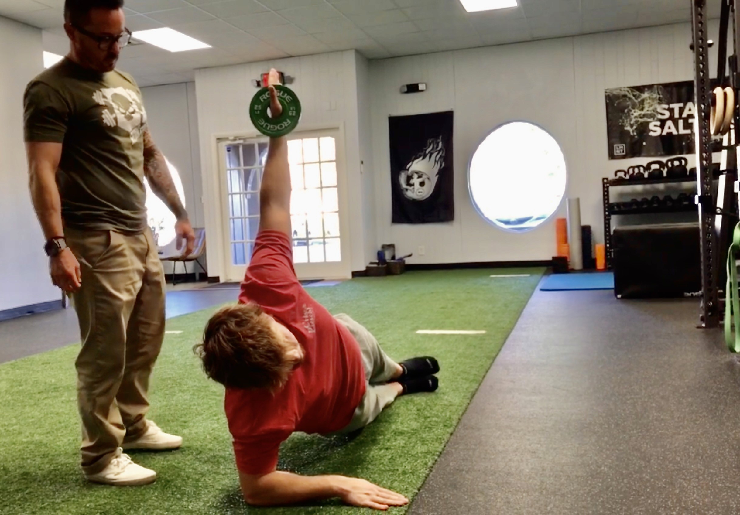 An athletic trainer coaching an athlete in a gym space.