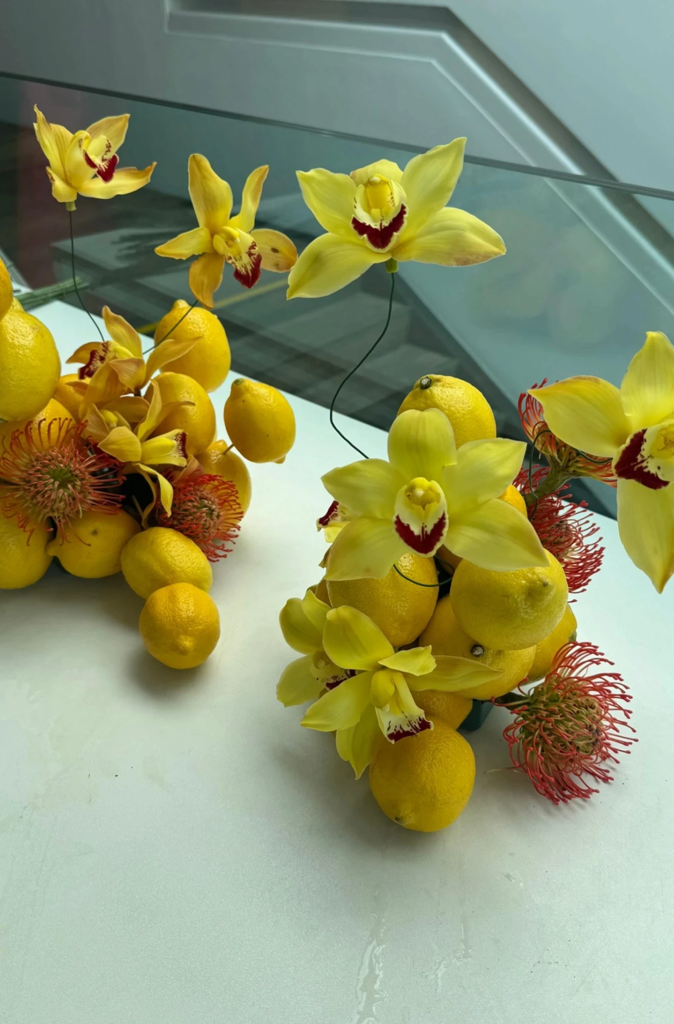 Arreglo floral con hortensias verdes, repollos y amaranto rojo colgante sobre una chimenea de mármol ornamentada, con un espejo dorado de fondo