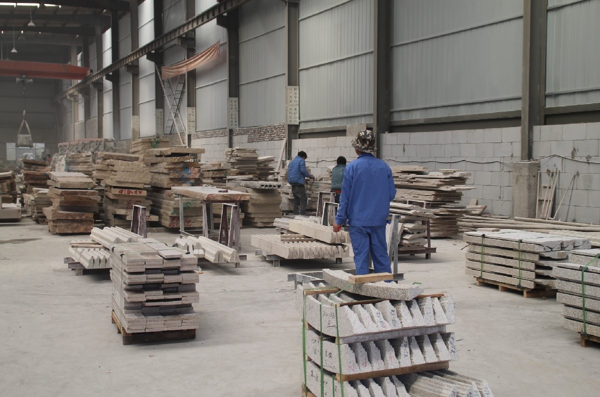 A large number of stone slabs neatly stacked in a stone processing factory, ready for further cutting and polishing.