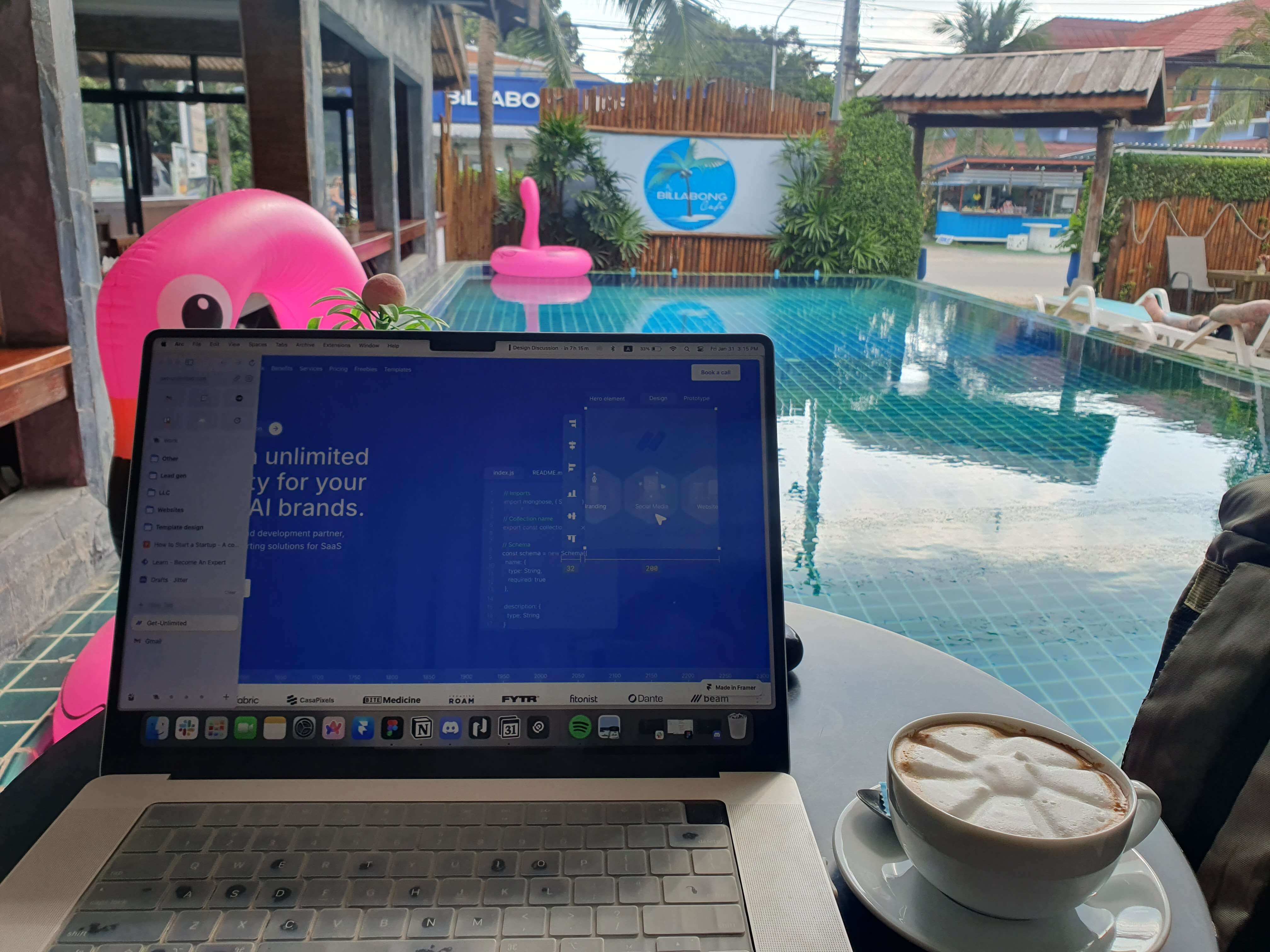 Photo of a laptop on a table with a coffee in front of a pool