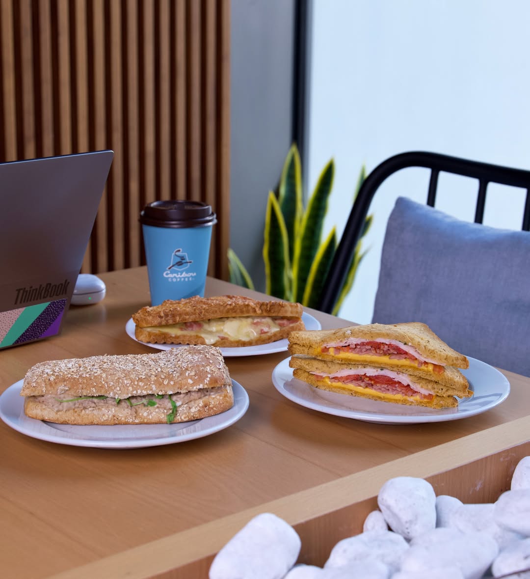 A table at Caribou Coffee with fresh sandwiches and a cup of coffee served 