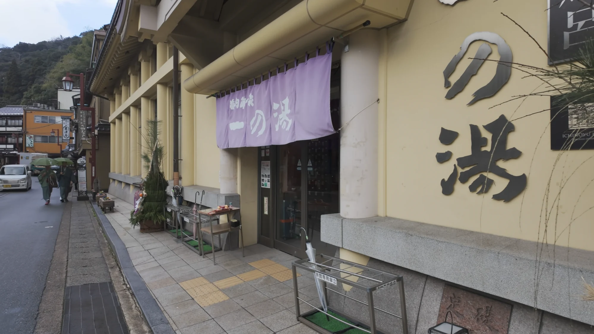The side elevation of Ichi-no-yu bathhouse with a purple noren and the character for hot water.