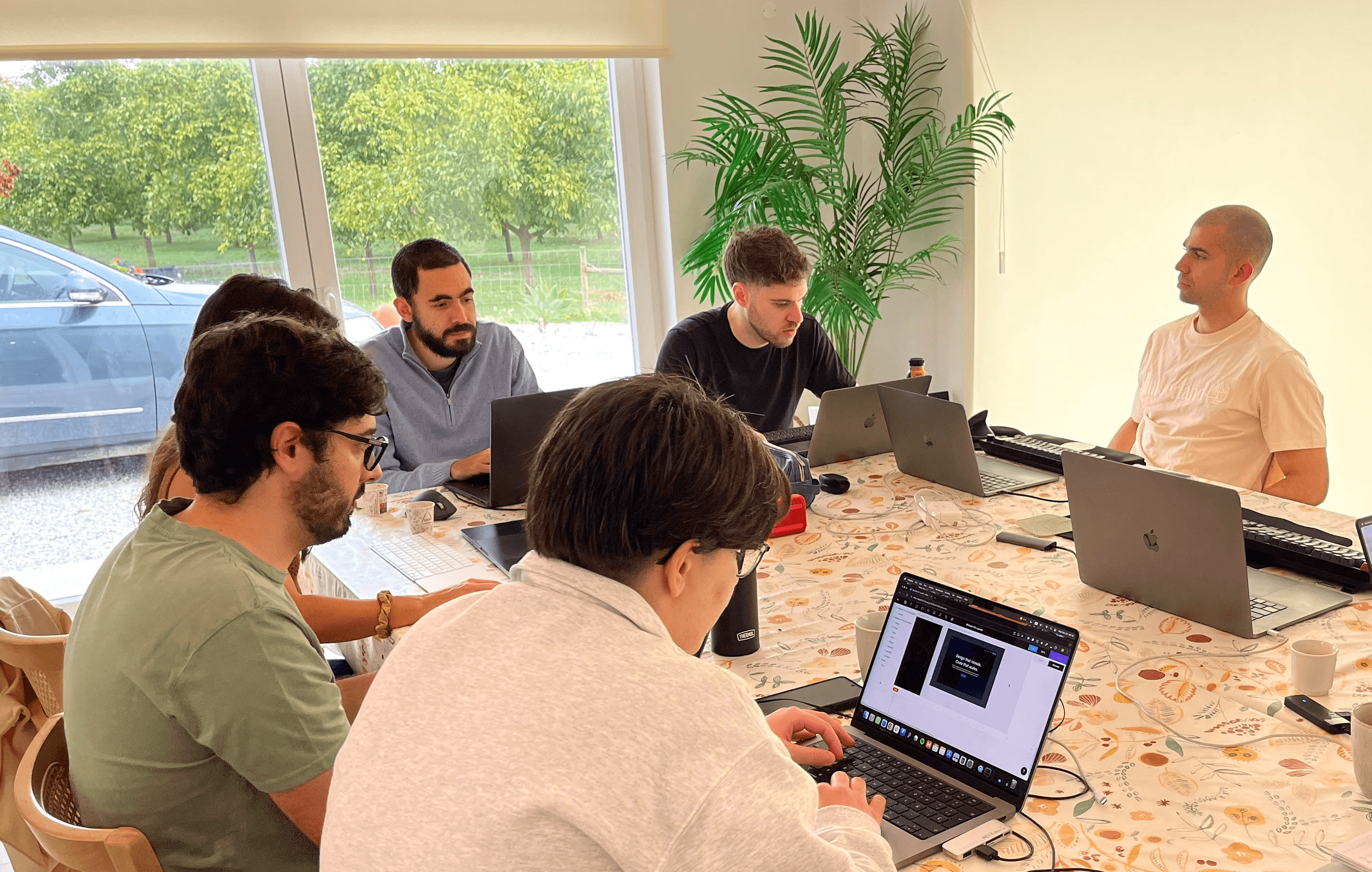 Three Concealed team members discussing a topic, where two are sitting and one, in the middle, is standing.
