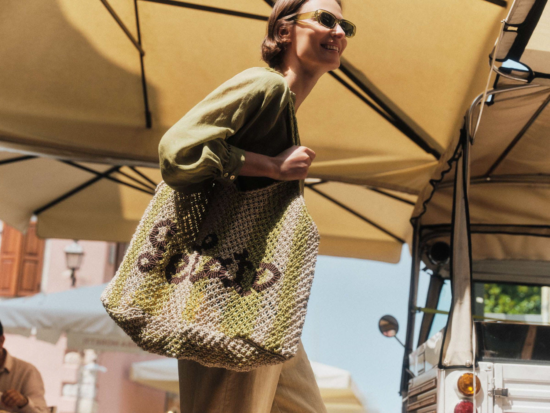 LANIUS model wearing a green blouse and carrying a crocheted tote bag outdoors