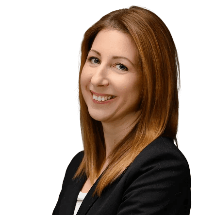 Mosolygó nő portréja világosbarna hajjal, fekete zakóban, kék háttér előtt.