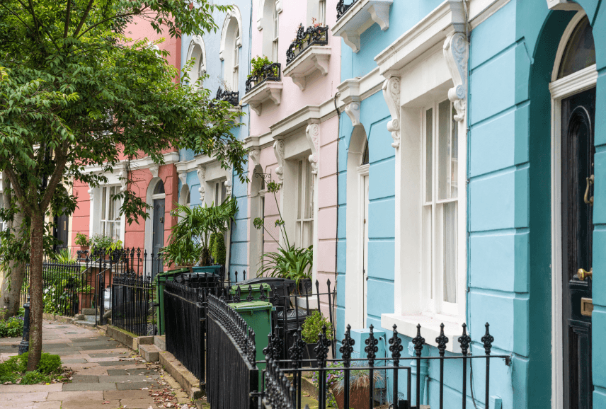Modern living room with abstract art, beige sectional sofa, indoor plants, and large windows.