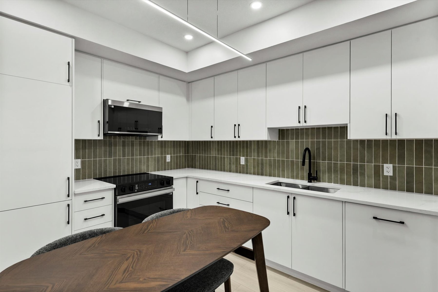 Legal suite kitchen after: white flat-panel cabinets, green tile backsplash and a walnut table