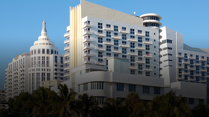 Two businessmen shaking hands in a modern, sunlit office setting.