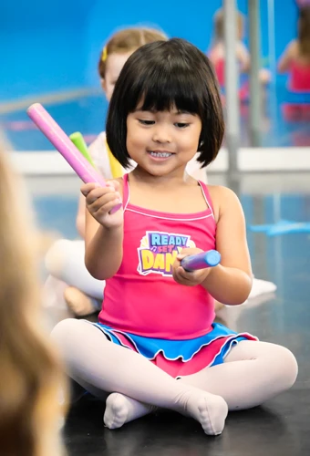 Ready set dance student using rhyth sticks in class