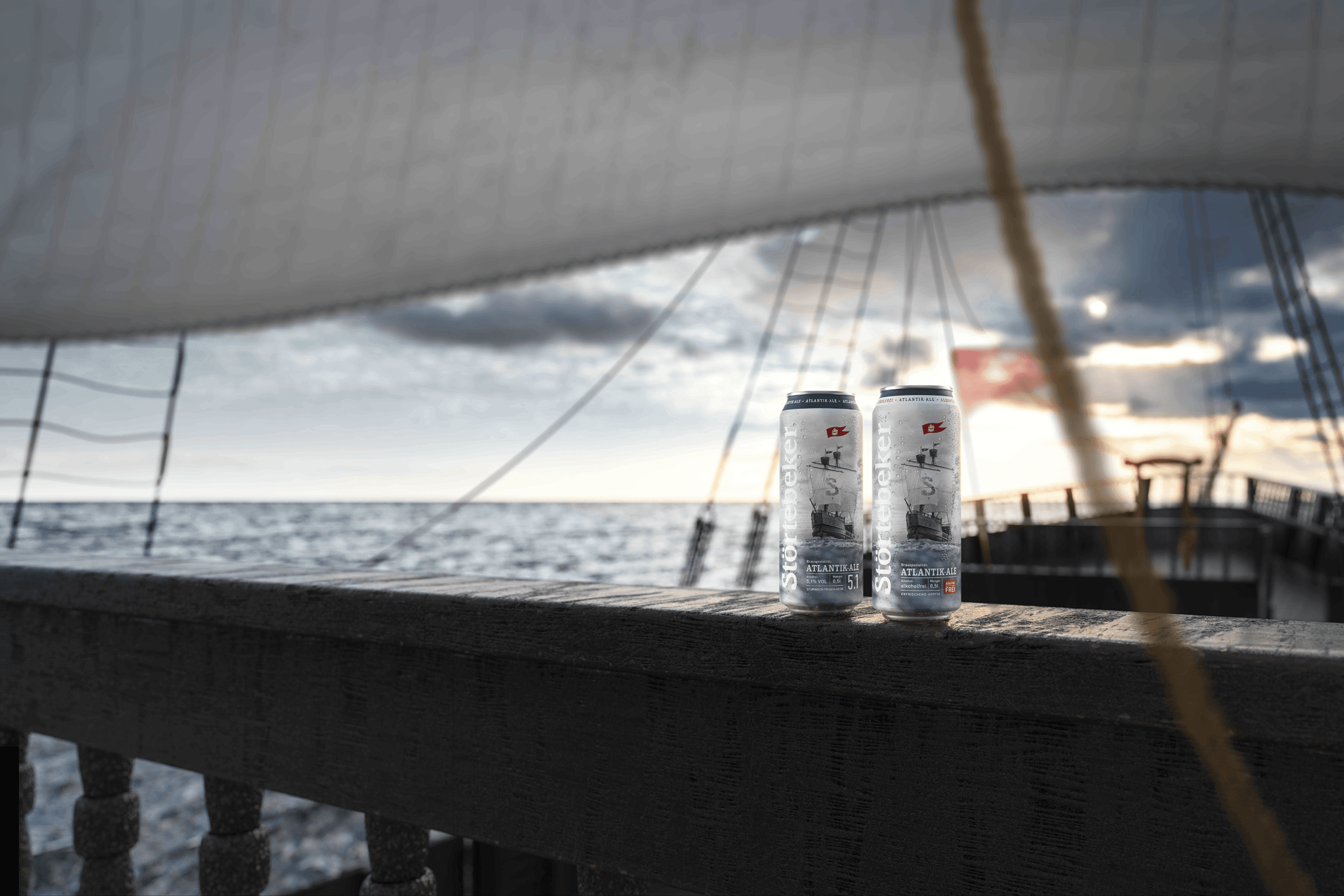 Two beer cans on a wooden railing of a boat.