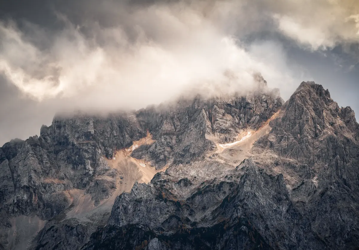 Close-up photo of epic mountains schrouded in low clouds during evening light in Slovenia.