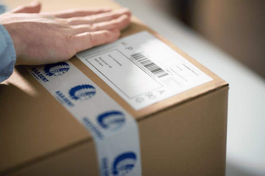 Imagen de una mano cerrando una caja de KAA Gent tras calcular los gastos de envío. 