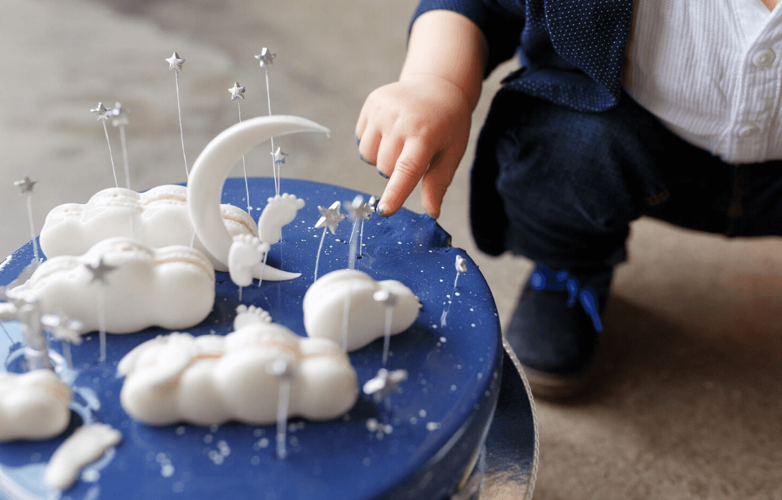 Baby reaching out to touch the frosting on his cake.