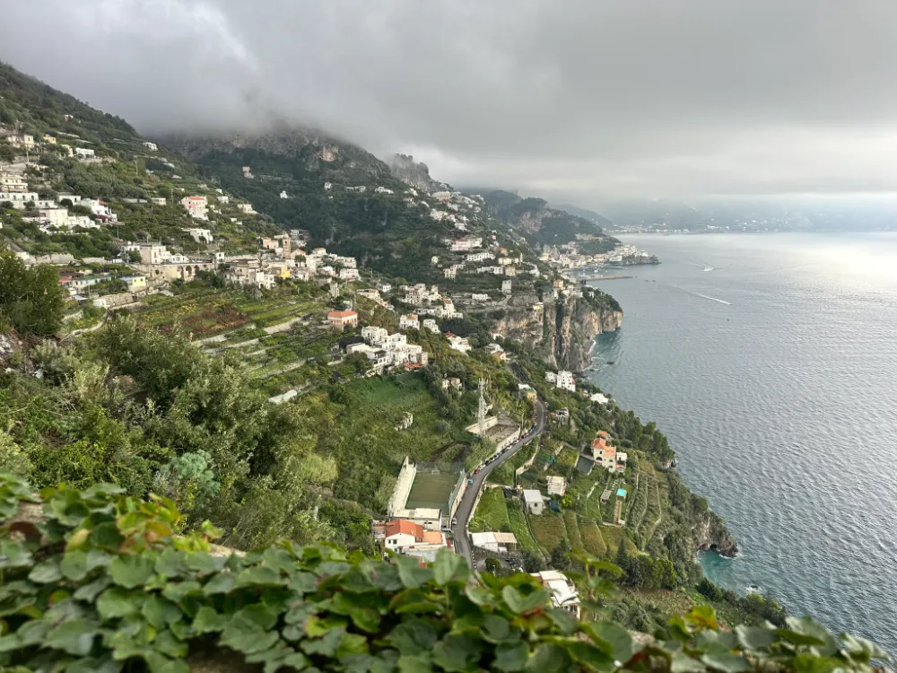 The Amalfi coastline seen from Monastero Santa Rosa, with a hillside village and mist on the mountains.