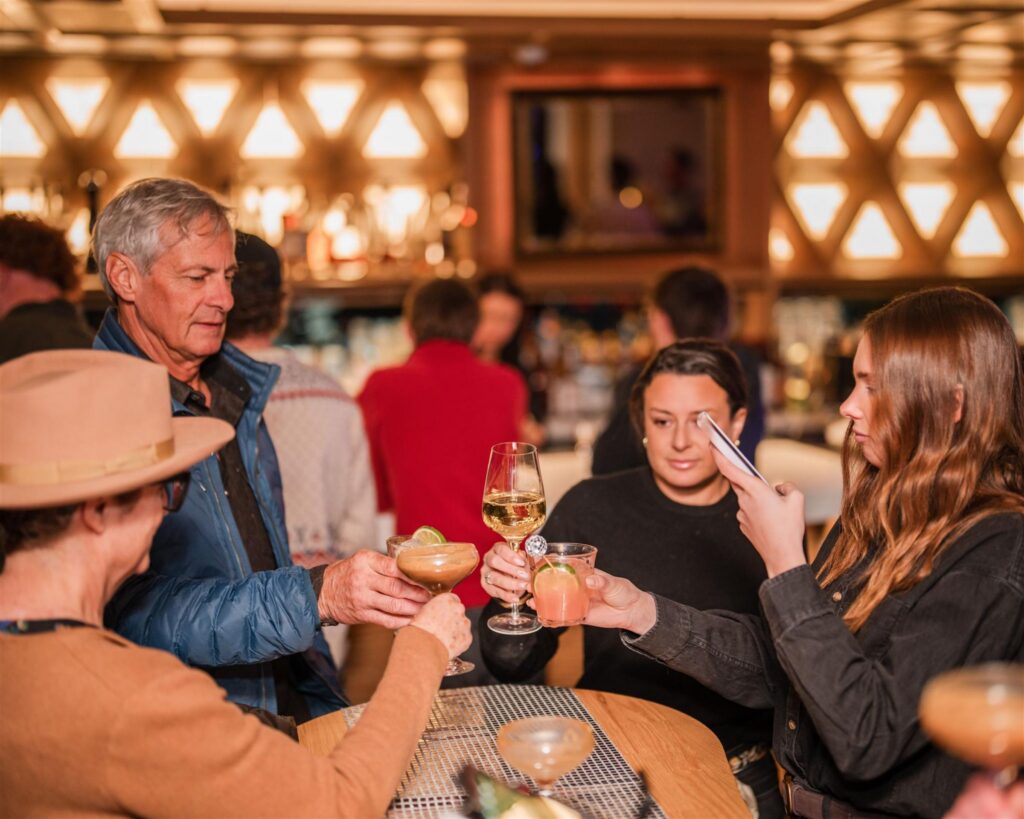 Guests raising cocktails together around a table