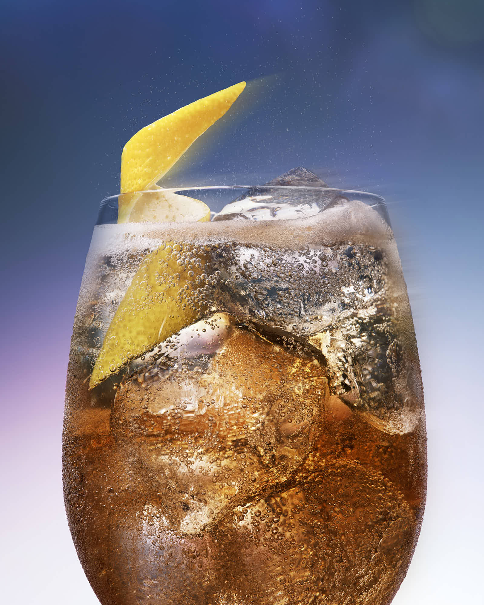 A glass filled with dark soda and ice, garnished with a lemon twist, against a gradient background.