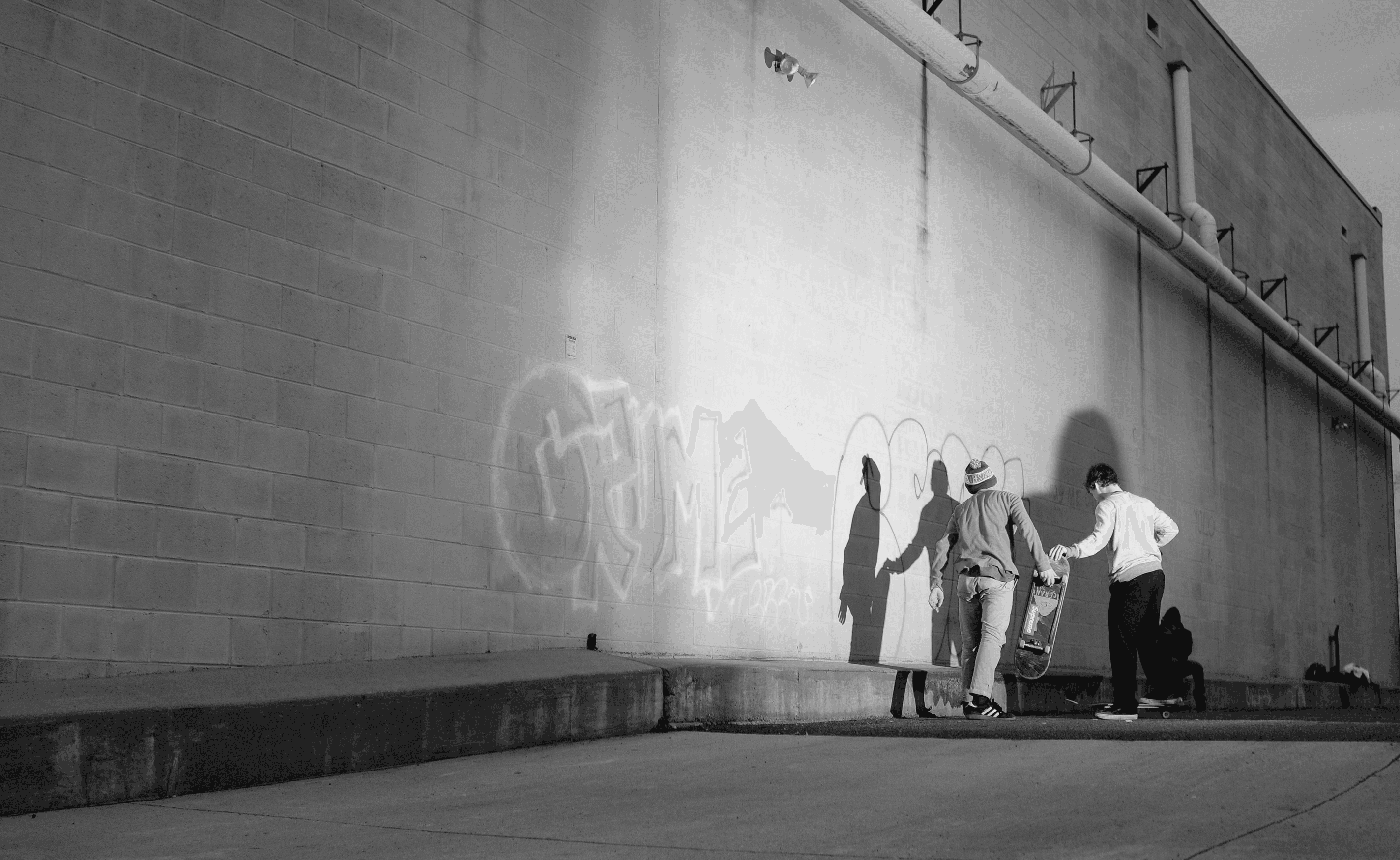 Photography of skateboarders by a ledge obstacle lit by a speed flash out of frame. 