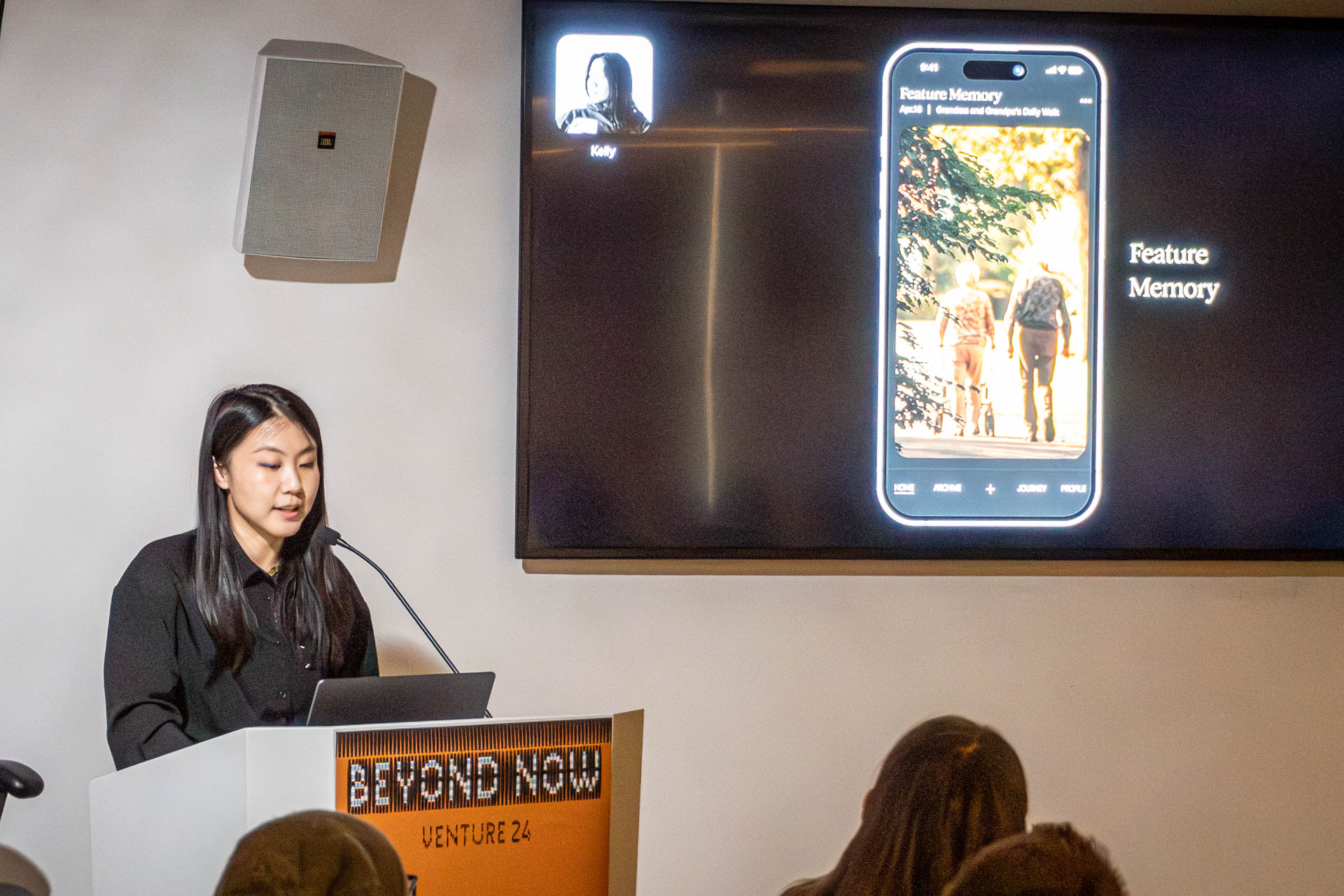 A lady at the podium giving a presentation to a class.