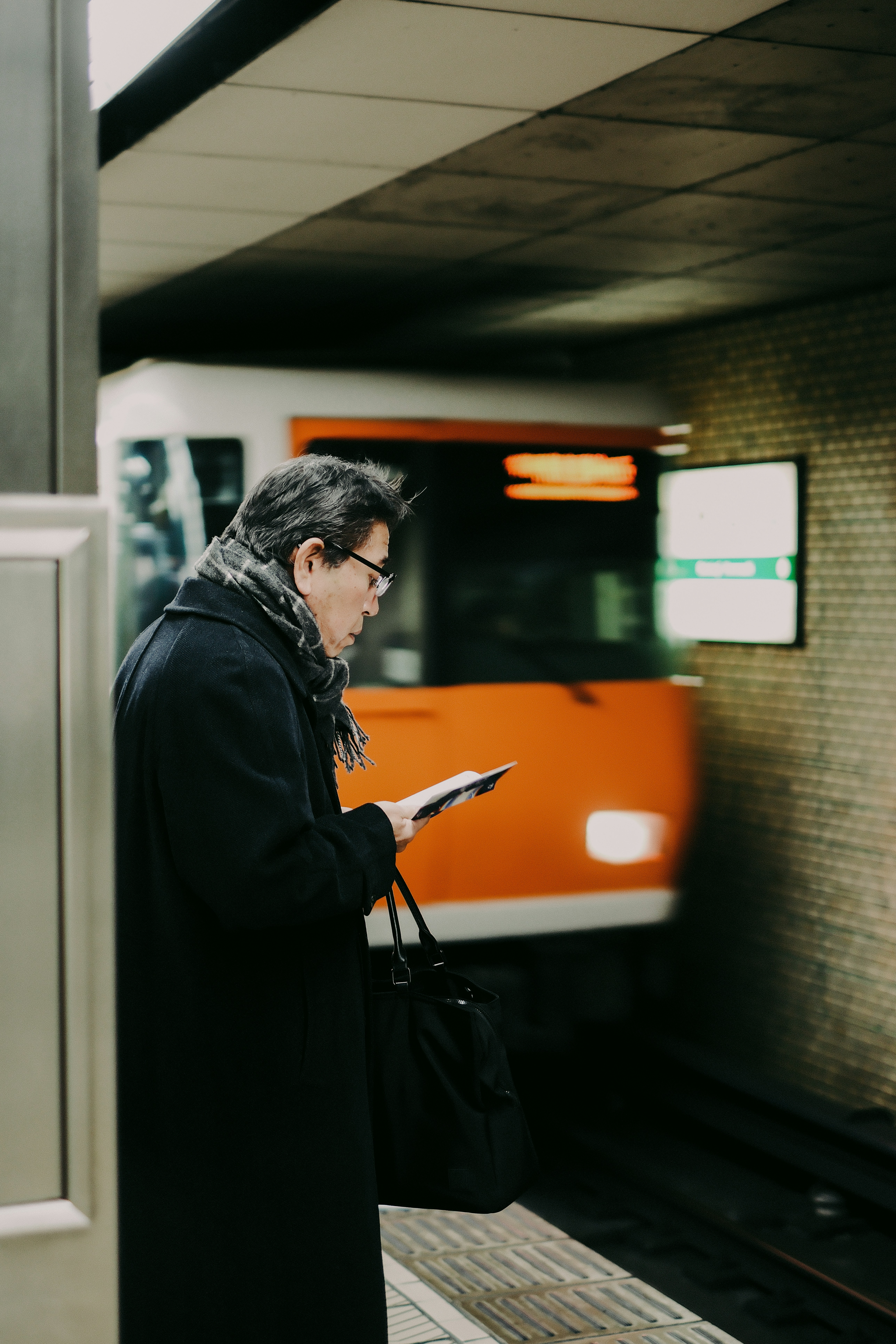 Man in coat reading on train platform