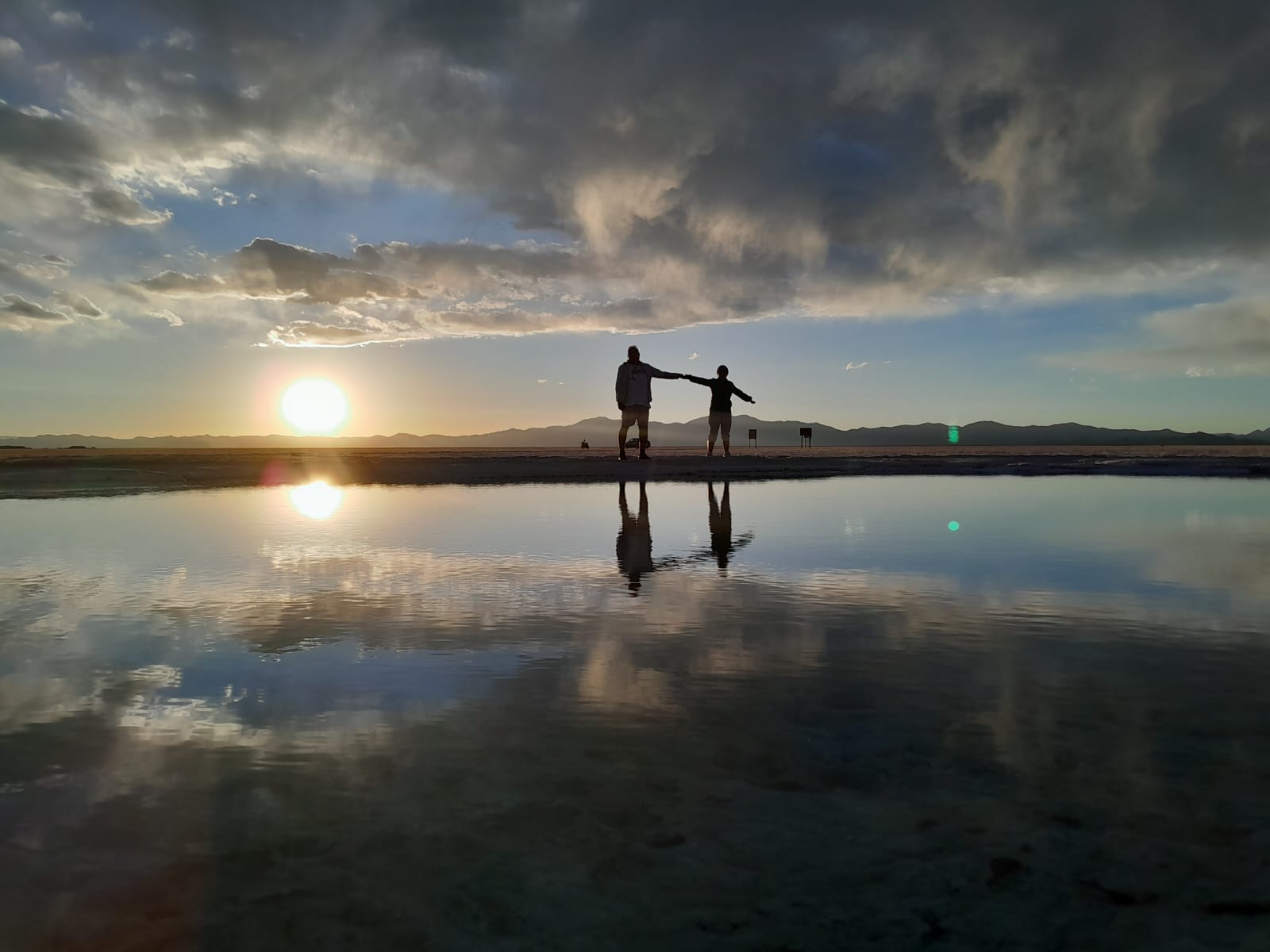 Mujer sentada sobre un tronco frente a una cascada doble en un bosque frondoso de Argentina.